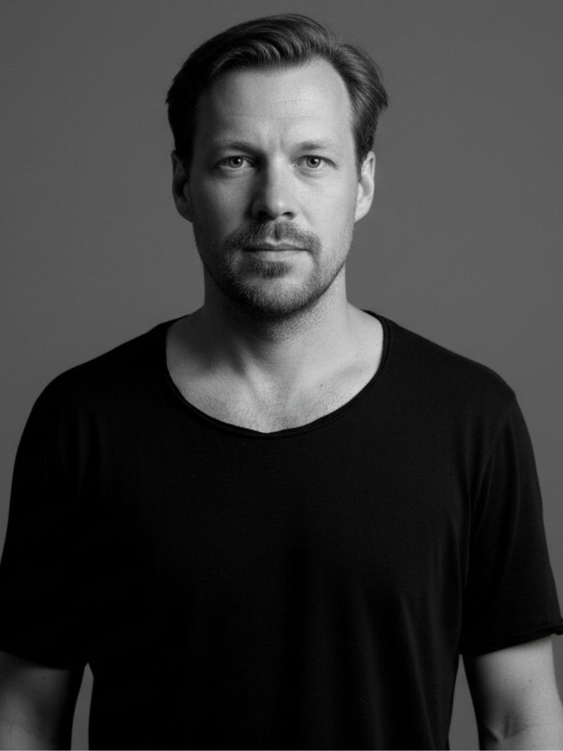 Black and white portrait of designer wearing a black t-shirt against a gray background. International design