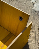 Detail of the wooden speaker chair featuring an integrated circular speaker driver within its angled backrest. The exposed wood grain and geometric construction emphasize its handcrafted furniture and audio design.
