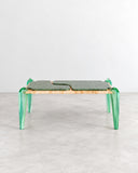Sculptural Acquamarina table featuring a slim rectangular top and translucent aqua-green legs with a fluid, organic profile. The vibrant finish and lightweight construction create a distinctive contemporary furniture piece.
