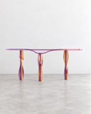 Sculptural Medusa console table featuring a slim translucent pink-purple top and three twisted, organically shaped legs with iridescent finishes. The fluid forms and vivid colors give this contemporary console a distinctive artistic character.