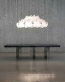 Modern dining table with a large, intricate pendant light against a concrete wall. BLACK MOON | Modern Contemporary Table | Limited Edition