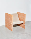 Sculptural chair crafted from Travertine Rosso stone. A designer seating piece showcasing rich natural colour and texture.