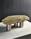 ONI coffee table featuring a sculptural onyx top with natural green and warm veining. Cylindrical metal legs create a contemporary designer table for luxury interiors.