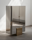 Sculptural storage cabinet crafted from reflective metal panels. A designer armoire with a contemporary architectural profile.