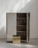 Reflective metal storage cabinet with an architectural silhouette. A luxury furniture piece for sophisticated interiors.
