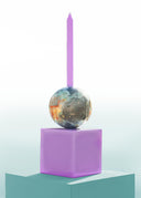Globe on a purple cube with a purple candle against a light blue background