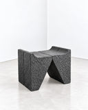 Alentes Atelier Cathrdra Seat featuring a bold, angular silhouette with sharply folded sides and a deeply textured dark finish. Its architectural geometry and sculptural form make it a distinctive contemporary accent seat.