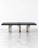 Alex Turco Black Moon Dining Table featuring a long, rectangular black tabletop supported by a series of sleek metallic legs. Its strong linear profile and contrasting finishes create a refined contemporary centrepiece for dining spaces.