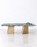 Alex Turco Lapponio Dining Table featuring an elongated, organically shaped green-grey top with distinctive natural veining and angular pedestal supports. Its expressive surface pattern and sculptural base bring a bold natural-material aesthetic to contemporary dining interiors.