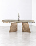 Alex Turco Vermont Dining Table featuring a long, irregularly edged stone-look top supported by substantial angled pedestal legs in warm, earthy tones. Its natural surface variation and architectural silhouette make it a distinctive statement for contemporary dining spaces.