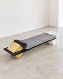 CoExist daybed featuring a pale elongated upholstered or stone-toned surface with sculptural contrasting end supports. The minimalist horizontal silhouette emphasizes material contrast and contemporary architectural design.