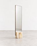 Full-length CoExist mirror featuring a slim vertical reflective panel and a sculptural green onyx base with natural stone patterning. The combination of reflective glass and richly veined stone creates a refined contemporary accent.