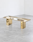 Contemporary X bureau featuring a slim rectangular work surface with a reflective metallic finish and geometric gold-toned supports. The streamlined construction combines functional workspace with sculptural modern design.