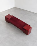 CoExist Redux bench in a vibrant rouge red finish with a long, low rectangular seat and block-like supports. The monolithic silhouette creates a bold contemporary seating piece.