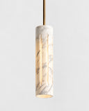 ETAMORPH Aura Pendant featuring an elongated cylindrical shade with translucent, naturally veined stone and a warm internal glow. Its refined vertical silhouette brings sculptural elegance to contemporary residential and hospitality lighting schemes.
