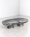 ETAMORPH Shell Coffee Table Calacatta Midnight Special Edition features an organic, elongated tabletop in dark marble with dramatic white and grey veining, supported by sculptural stone legs. Its flowing silhouette and bold natural pattern create a distinctive statement for luxury interiors.