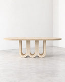 ETAMORPH Trifold Dining Table features a long, slim oval tabletop supported by three distinctive U-shaped legs in a light natural stone finish. Its repeated curved supports and clean architectural lines create a sculptural centrepiece for contemporary dining interiors.