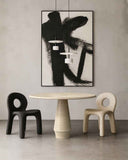 Modern dining room with a round table and two chairs, featuring abstract art on the wall.