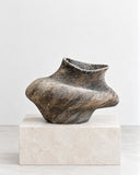 Genaro Hoepfner RTW01 Stoneware Object featuring a low, irregularly rounded body, a sculpted narrow opening, and a richly variegated brown and charcoal surface. Its organic contours and expressive texture make it a distinctive sculptural accent for contemporary interiors.