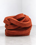 IAMMI Brrrick Lounge Chair featuring an unconventional sculptural form composed of thick, interlocking upholstered curves in a rich rust-orange tone. Its tactile surface and expressive, layered silhouette create a distinctive statement in contemporary interiors.