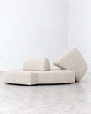 IAMMI Esperia Sofa Configuration 2 features a low, modular ivory upholstered base paired with a separate angled back cushion. Its minimalist form and flexible arrangement offer a contemporary approach to relaxed lounge seating.