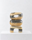 LS-04 yellow marble sculpture featuring stacked rounded forms, an open central detail, and a sculptural arched base. The warm golden and cream veining highlights the natural variation of the stone.