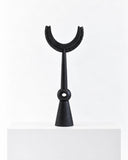 Dziü wood sculpture featuring an abstract stacked composition with rounded horizontal forms and a distinctive curved base. The dark natural wood finish and geometric silhouette highlight the expressive character of handcrafted sculptural design.