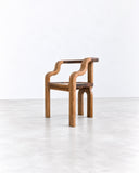 METAMO Marea Armchair featuring a sculptural wooden frame with fluid, curved armrests, integrated back supports, and visible natural wood grain. Its warm finish and continuous organic lines bring a distinctive handcrafted character to contemporary seating.