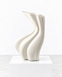 Niccolo Poggi Sinuo Blanco Vase featuring a sculptural white finish with flowing, twisted contours and a flared asymmetrical opening. Its fluid silhouette and softly reflective surface create a contemporary decorative statement.