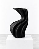 Niccolo Poggi Sinuo Nero Opaco Vase featuring a matte black finish, flowing sculptural curves, and an elongated, asymmetrical opening. Its dramatic monochromatic look and fluid form bring bold contemporary character to interior spaces.