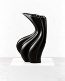 Niccolo Poggi Sinuo Nero Vase featuring a glossy black finish with undulating, twisted contours and a flared sculptural opening. Its reflective surface highlights the vase’s fluid geometry, making it a distinctive accent for contemporary interiors.