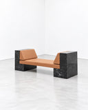 Noemi Saga Ini Marble Daybed featuring a long cognac-toned upholstered cushion supported by substantial black marble end blocks. The contrast between warm upholstery and dark stone creates a refined, architectural statement for luxury residential and hospitality interiors.