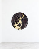 Onno Adriaanse Delta Mirror featuring a round reflective surface framed by an expressive dark pattern with flowing cream and gold-toned details. Its organic, abstract design turns a functional mirror into a sculptural wall feature.