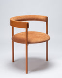 Sculptural upholstered chair in an almond fabric finish with soft curved lines. A designer dining chair crafted for contemporary luxury interiors.