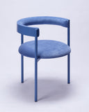 Designer dining chair upholstered in indigo fabric with elegant curved forms. Crafted as a contemporary seating piece for luxury interiors.