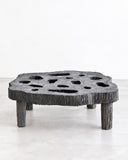 RIES Pasto Mesa Ratona Coffee Table featuring a low, rounded tabletop with irregular circular openings and chunky legs in a dark, heavily textured finish. Its organic geometry and raw, sculptural appearance make it a striking contemporary living room centrepiece.