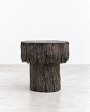 RIES Pasto Stool featuring a compact cylindrical form with a thick rounded seat and a deeply textured dark surface. Its monolithic proportions and rugged finish make it a distinctive sculptural accent for contemporary interiors.