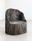 RIES Pasto Trono Armchair featuring a low, throne-inspired silhouette with a broad rounded seat and an enveloping, irregularly contoured backrest. Its heavily textured dark finish and solid sculptural form give the chair a distinctive organic character.