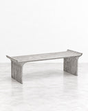 RIES Tori Coffee Table featuring a long rectangular top with subtly raised ends and two substantial sculptural supports in a pale grey, textured finish. Its minimalist profile and architectural proportions create an understated contemporary centrepiece.
