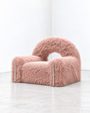 Richard Yasmine Furrybum Pink Fur Armchair featuring a low, rounded silhouette upholstered in plush pink fur with a distinctive arched back and integrated armrests. Its soft texture and playful sculptural form bring a bold accent to contemporary interiors.