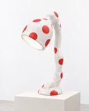 Ryan Mercer Big Lamp featuring a sculptural white base and curved stem decorated with bold red polka dots, topped with an oversized angled lampshade. Its playful pattern and organic silhouette transform functional lighting into a striking contemporary design statement.