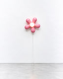 Ryan Mercer Bloom Lamp featuring a pink, flower-shaped light with rounded petals arranged around a central bulb. Its minimalist, floral silhouette offers a playful interpretation of contemporary wall lighting.