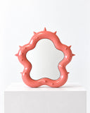 Ryan Mercer Spiky Mirror featuring an irregular, coral-pink frame accented with sculptural spikes around its reflective centre. Its expressive outline transforms a functional mirror into a bold contemporary design object.