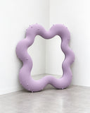 Ryan Mercer Toothpaste Floor Mirror featuring a full-length reflective surface surrounded by a thick, undulating lavender frame. Its soft, irregular contours and distinctive colour bring a playful sculptural accent to contemporary interiors.