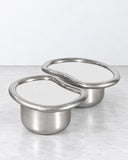 SECOLO x EERA Laghi M coffee table featuring a circular silver-toned reflective tabletop and a cylindrical metallic pedestal base. Its streamlined form and polished finish create a minimalist contemporary centerpiece.