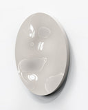 Sculptural round wall object featuring a softly irregular form and glossy white surface with subtle dimensional relief. Its organic silhouette creates a refined contemporary accent for curated interiors.