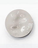 Close-up of the FRAME Round Freeform wall object showcasing its glossy white surface and softly undulating sculptural texture. The tactile design creates an expressive contemporary statement piece.