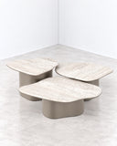 Fragment coffee tables featuring irregular pale stone tops arranged at varying heights on sculptural pedestal supports. The layered organic shapes create a versatile contemporary centerpiece with natural material character.
