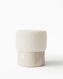 Sculptural HELVIS stool featuring a softly rounded upholstered seat over a smooth cylindrical base. The compact contemporary design combines tactile upholstery with a clean architectural silhouette.