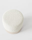 Top view of the HELVIS stool highlighting its softly rounded upholstered seat and organic silhouette. The tactile surface and minimalist form emphasize its contemporary sculptural character.